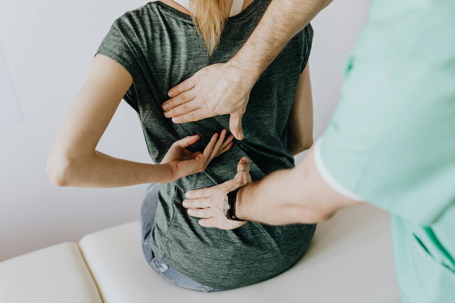 Close-up of chiropractor hands adjusting patient upper back on treatment table