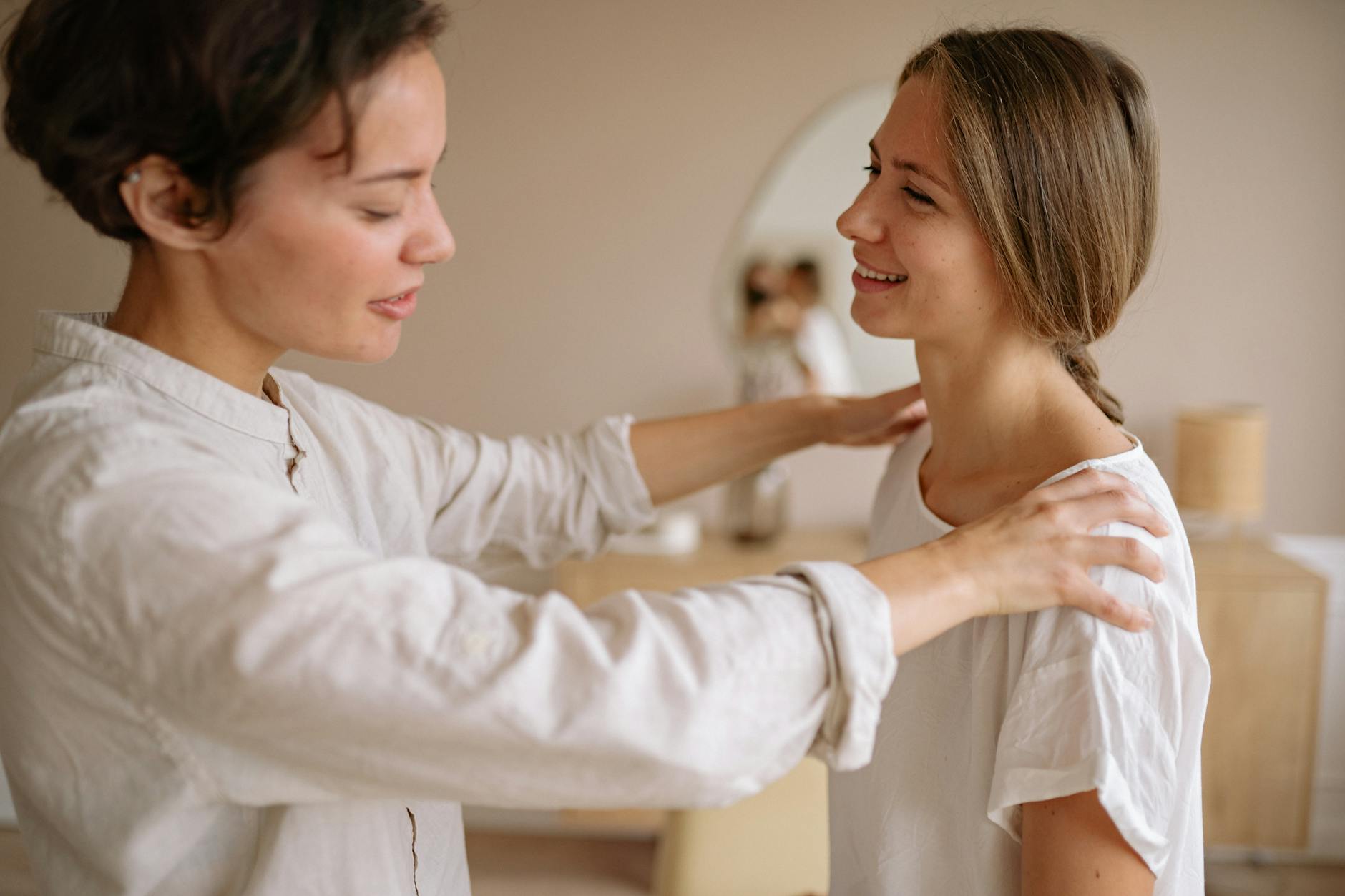 Licensed massage therapist working on patient shoulders in calm treatment room