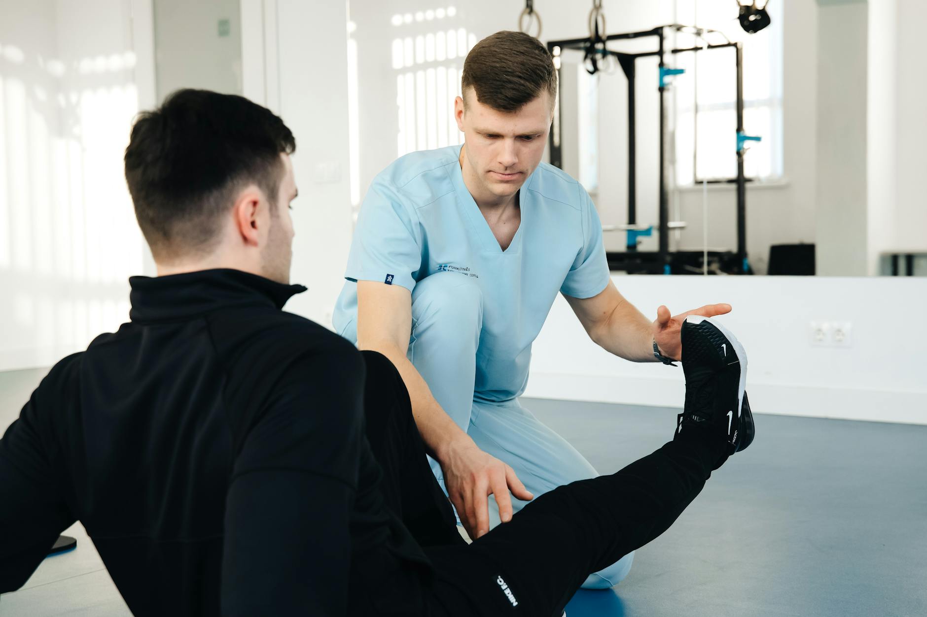 Practitioner guiding patient through assisted hamstring stretch in clinic
